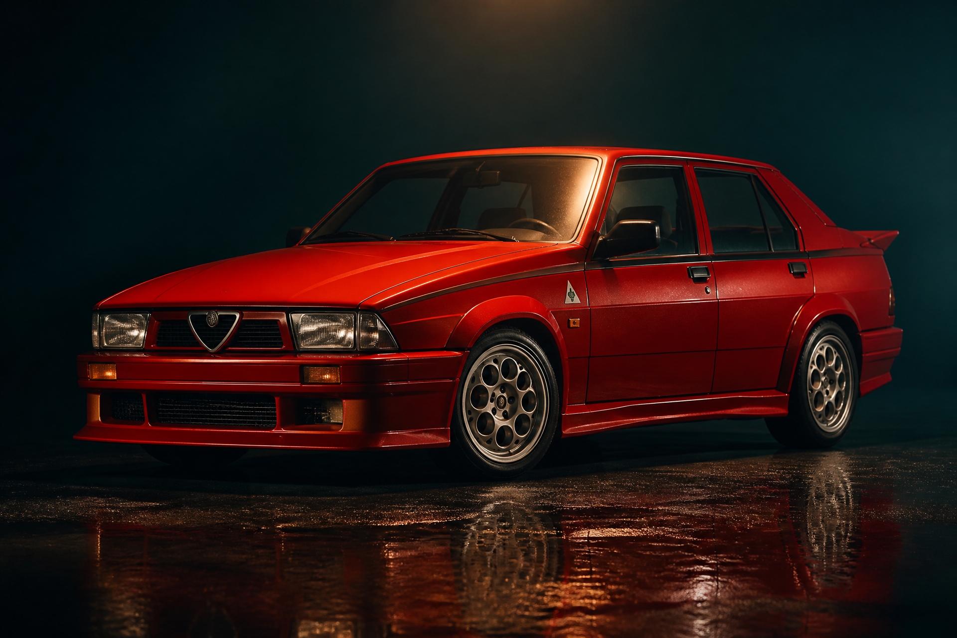Alfa Romeo Giulietta Turbodelta rossa fotografata di tre quarti anteriore in un set scuro con riflesso sul pavimento